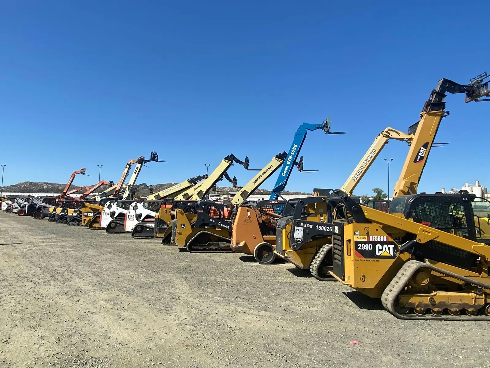 Row of telehandlers and skid steers on a lot